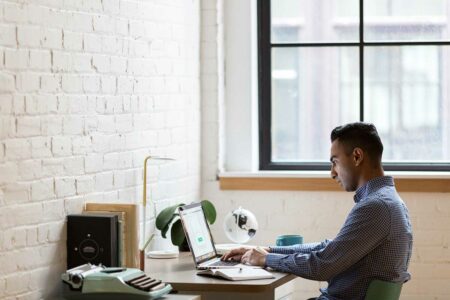 email marketing specialist working at a desk using a laptop to create email marketing campaigns