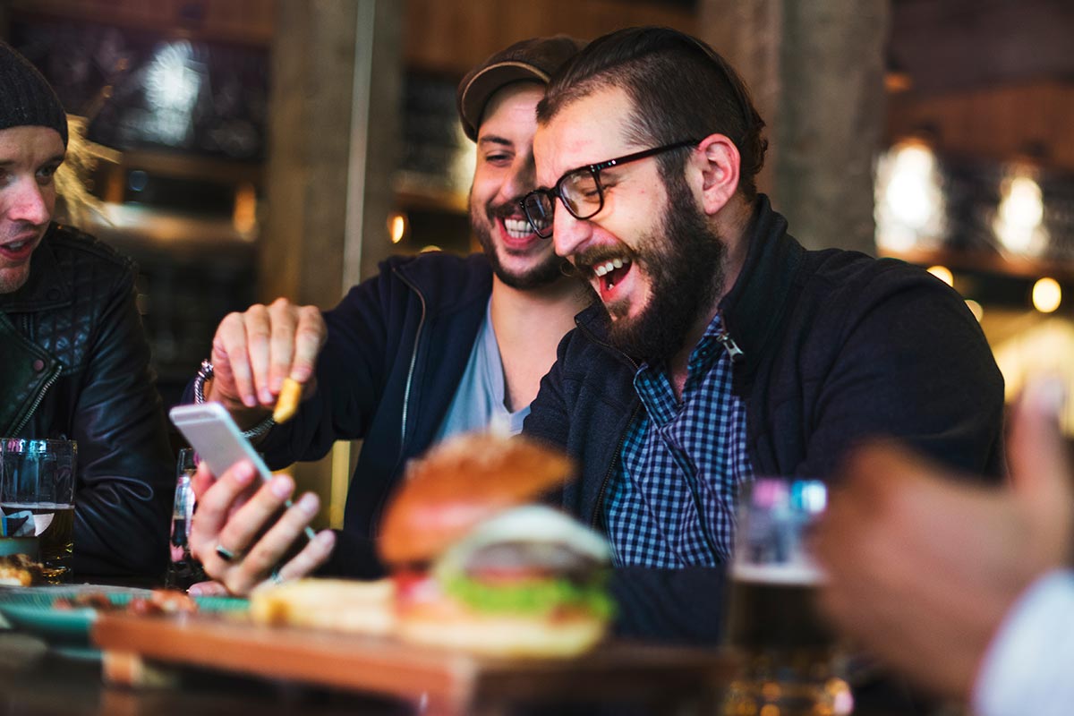 three men laughing and working on social media campaign ideas