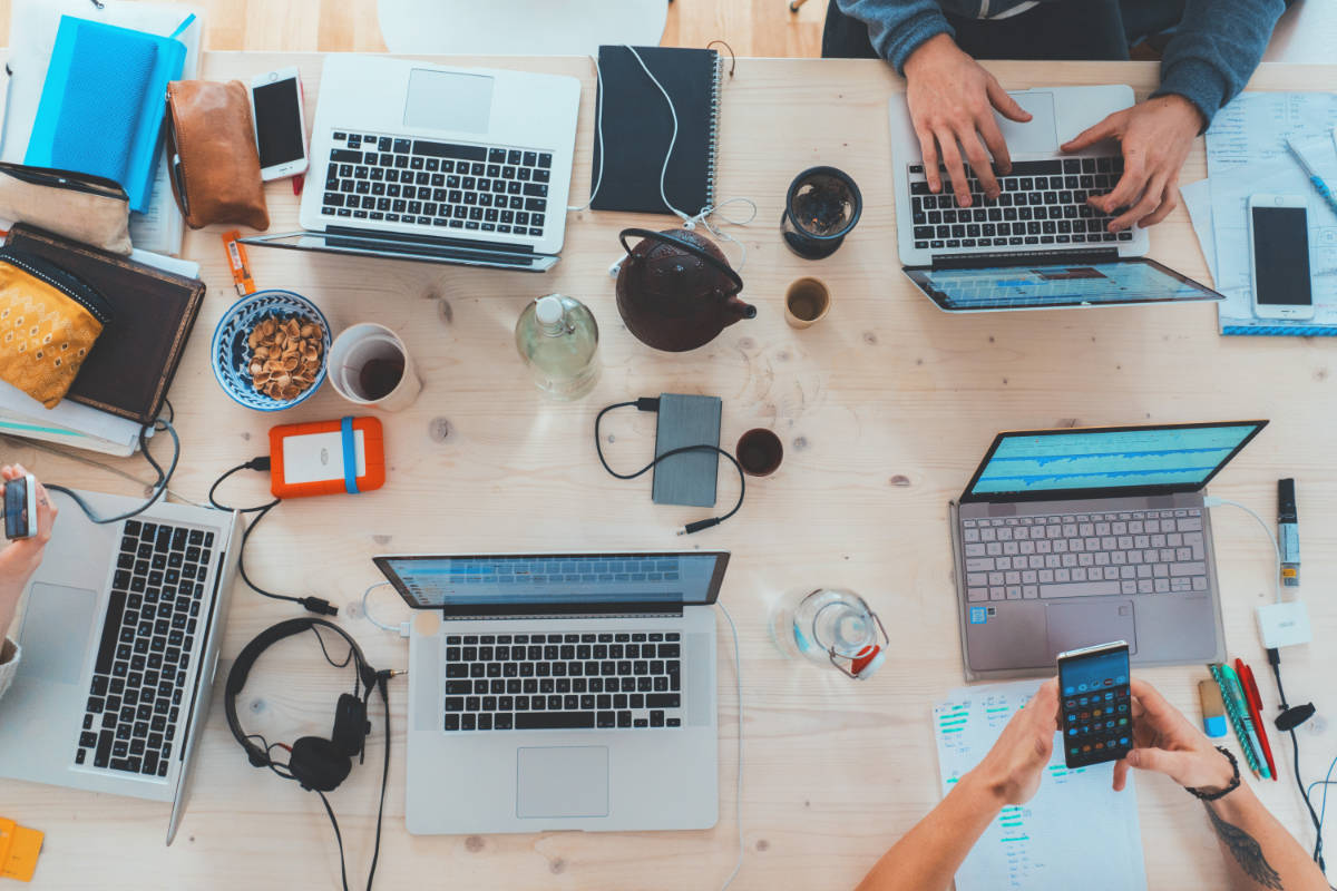 overhead view of a team of Social Media Strategists collaborating on laptops and mobile devices